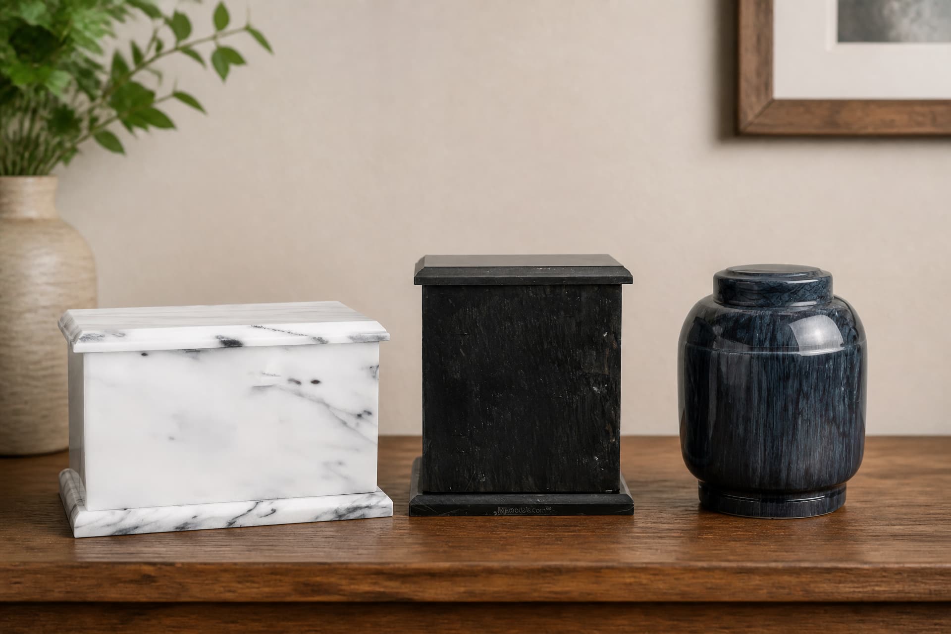 Three marble cremation urns on a wooden shelf in a family home: a white marble box urn, a black marble box urn, and a dark gray marbled vase urn